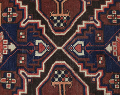 A close-up of a vintage Persian Bakhtiari rug featuring geometric floral motifs in red and blue.