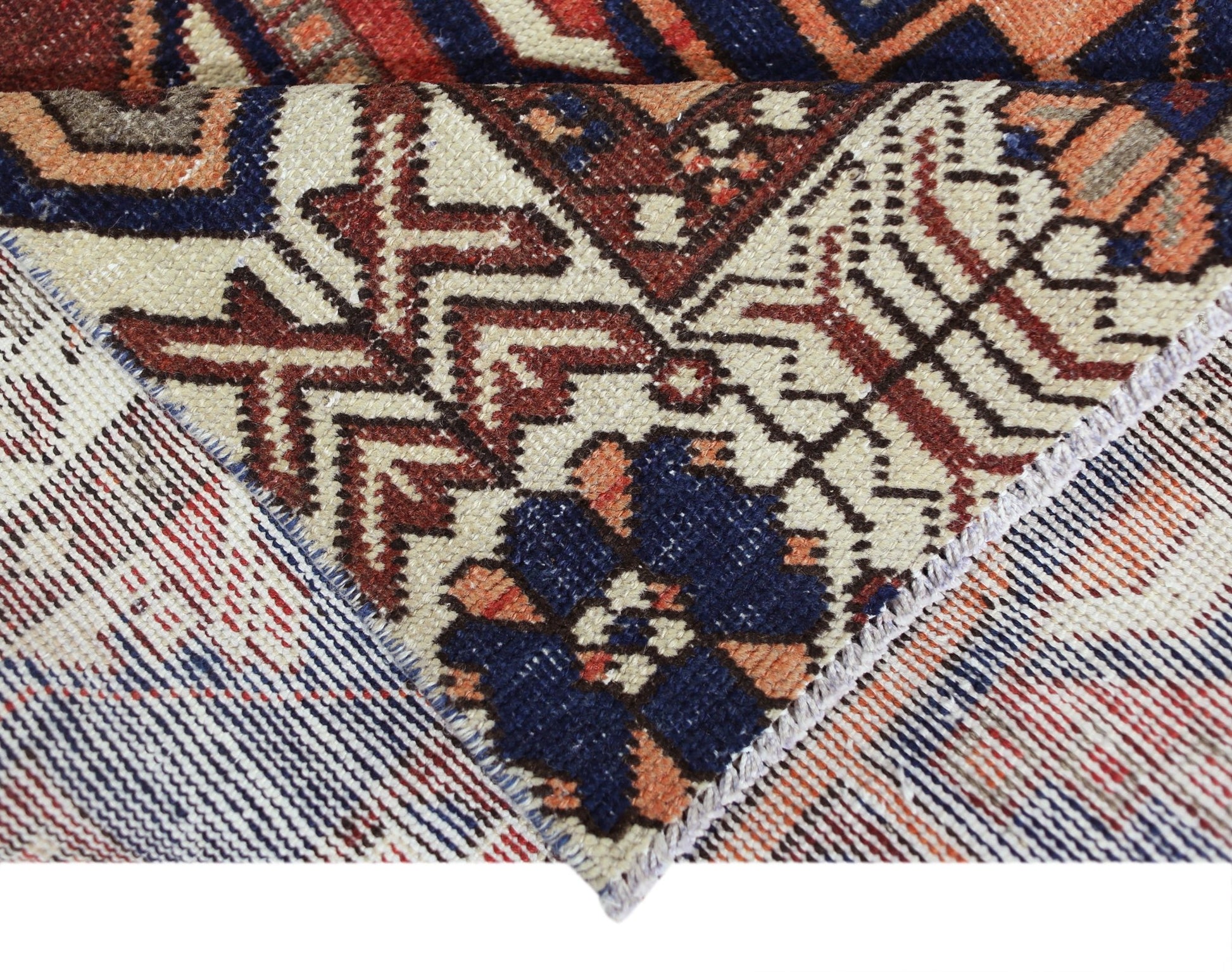 A close-up view of a vintage Persian Bakhtiari rug showing its intricate wool pile and cotton base.