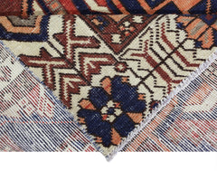 A close-up view of a vintage Persian Bakhtiari rug showing its intricate wool pile and cotton base.