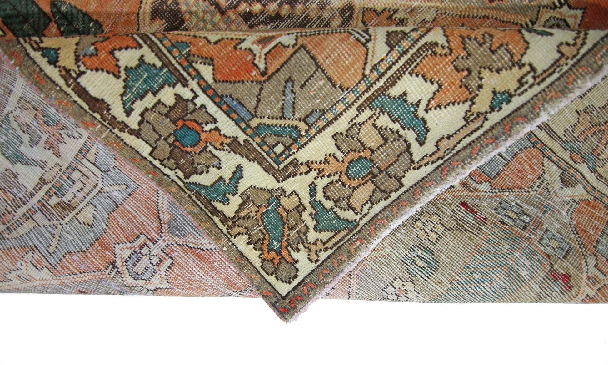 A folded corner of a vintage Persian Bakhtiari rug featuring intricate floral and geometric patterns.