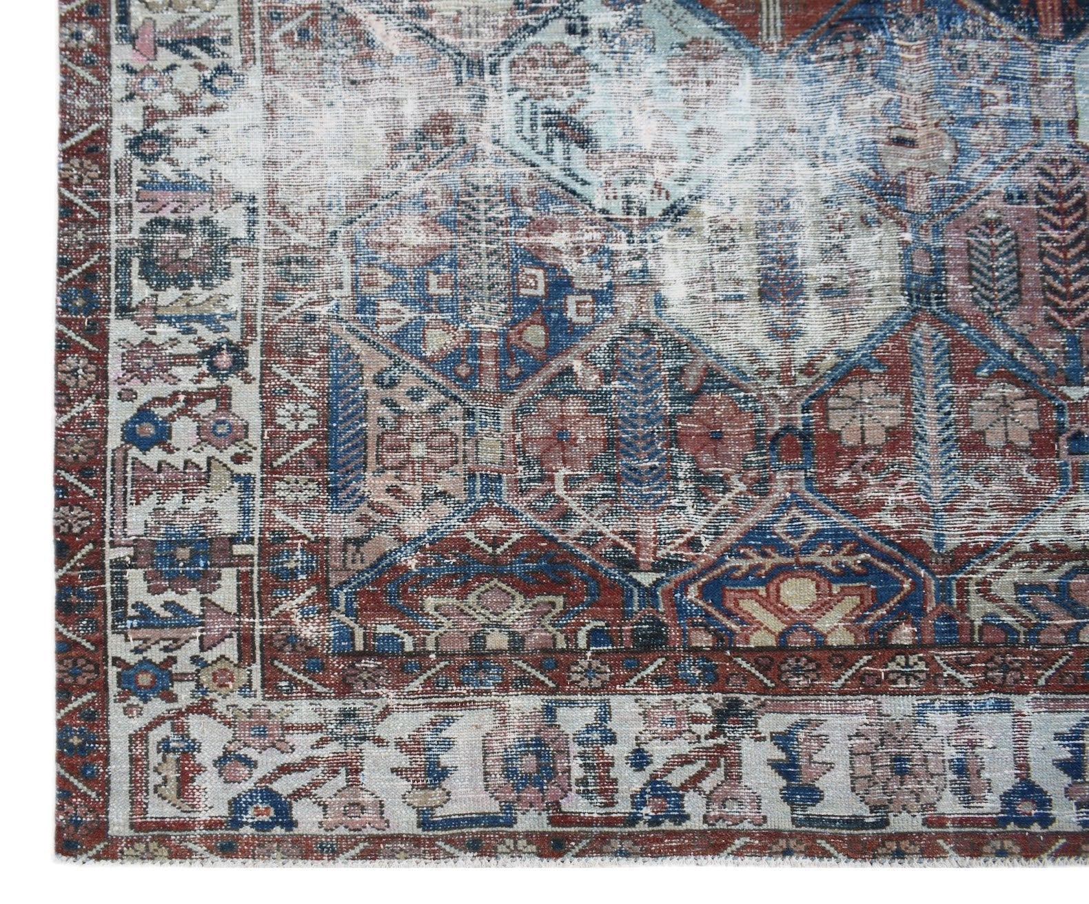 A vintage handwoven Persian Bakhtiari rug featuring a distressed geometric pattern in blue and red.