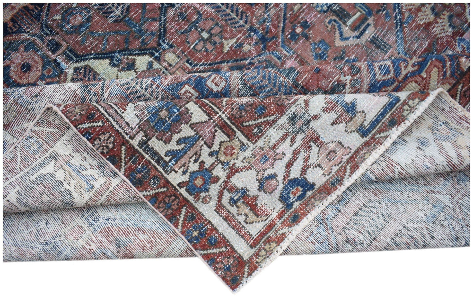 A vintage handwoven Persian Bakhtiari rug featuring a worn, intricate floral pattern in wool.