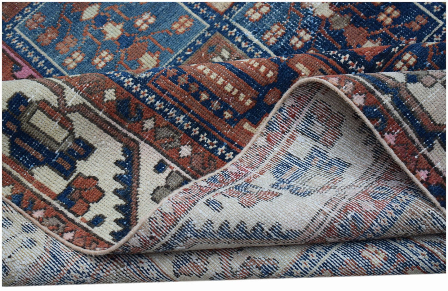 A vintage Persian Bakhtiari rug with a geometric pattern in blue, red, and cream wool.