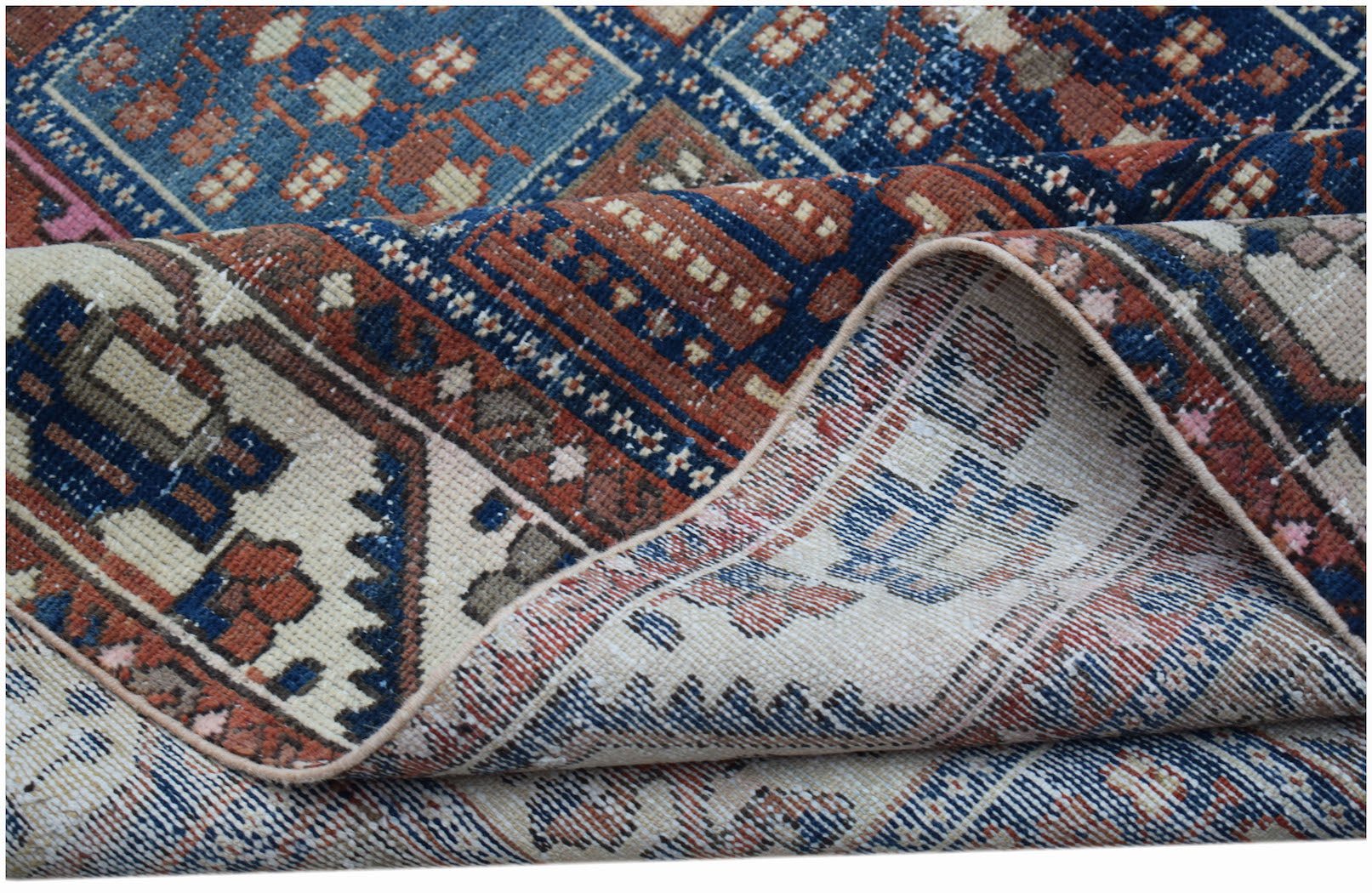 A vintage Persian Bakhtiari rug with a geometric pattern in blue, red, and cream wool.