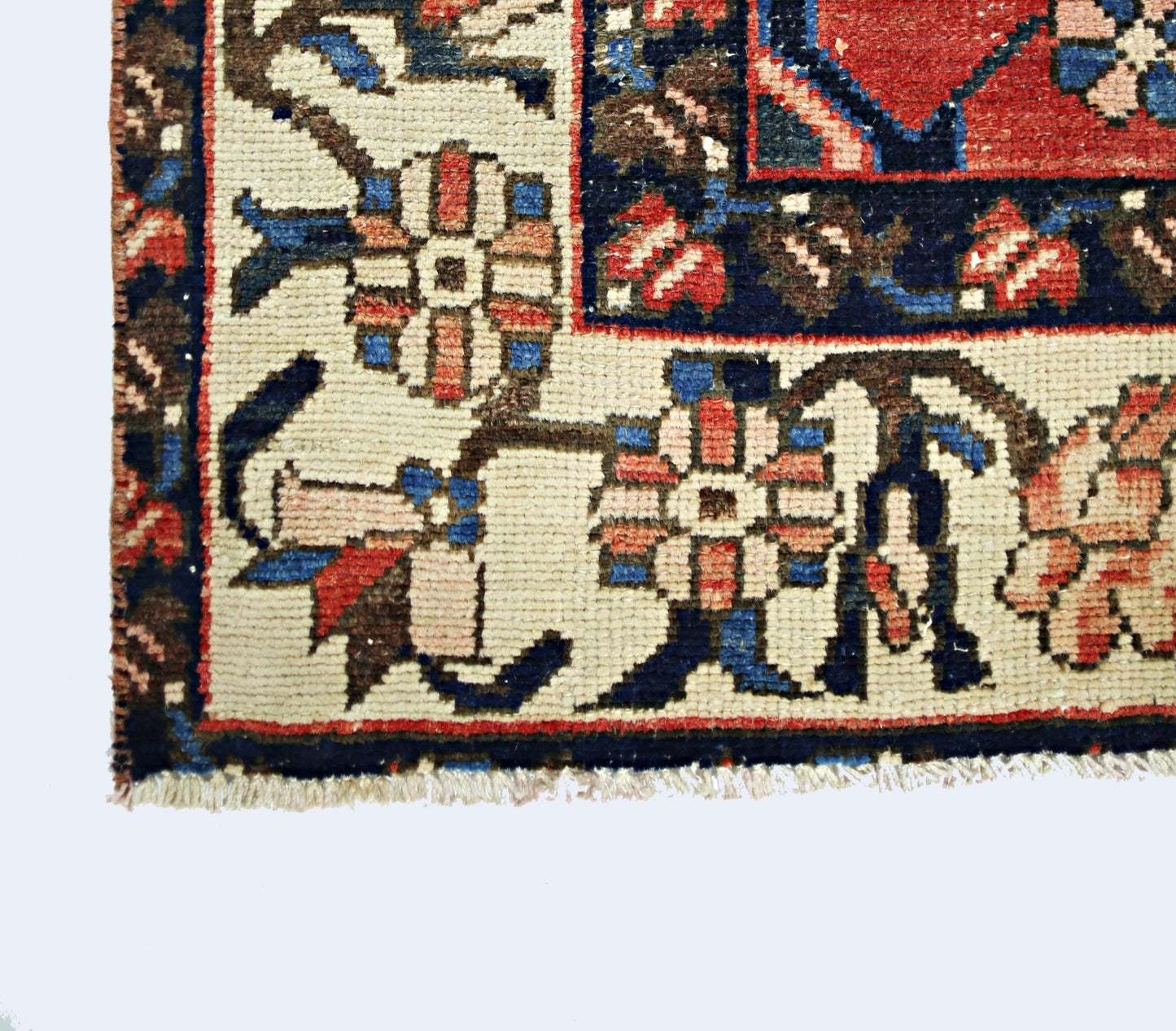 A corner detail of a vintage Persian Bakhtiari rug featuring floral patterns in red and blue.