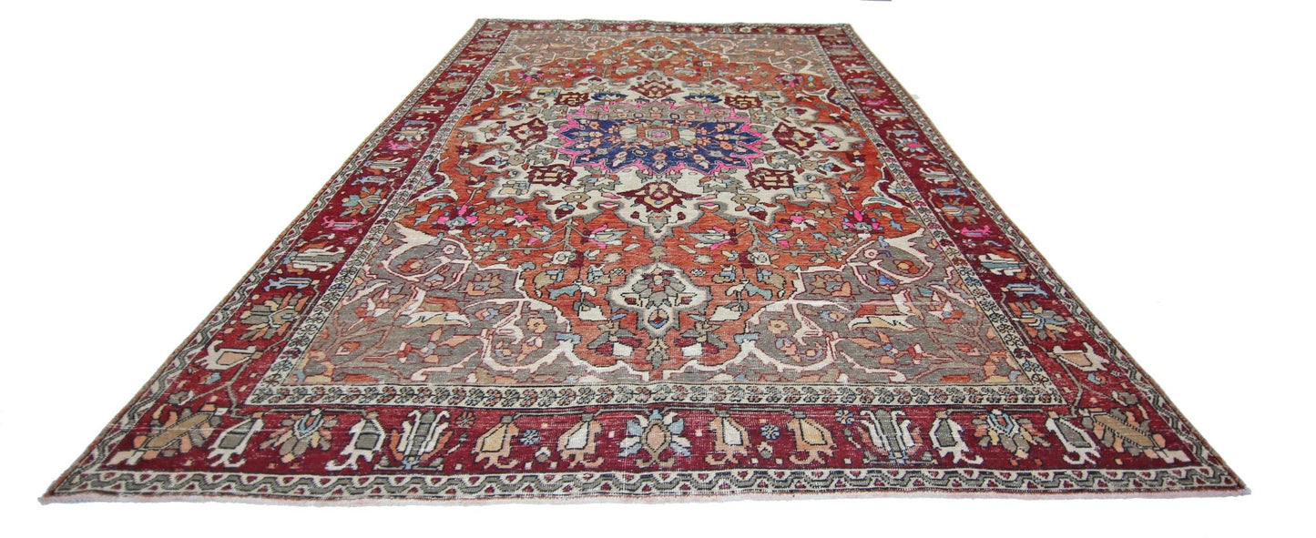 A vintage Persian Tabriz rug featuring a central floral medallion on a rust and cream background.