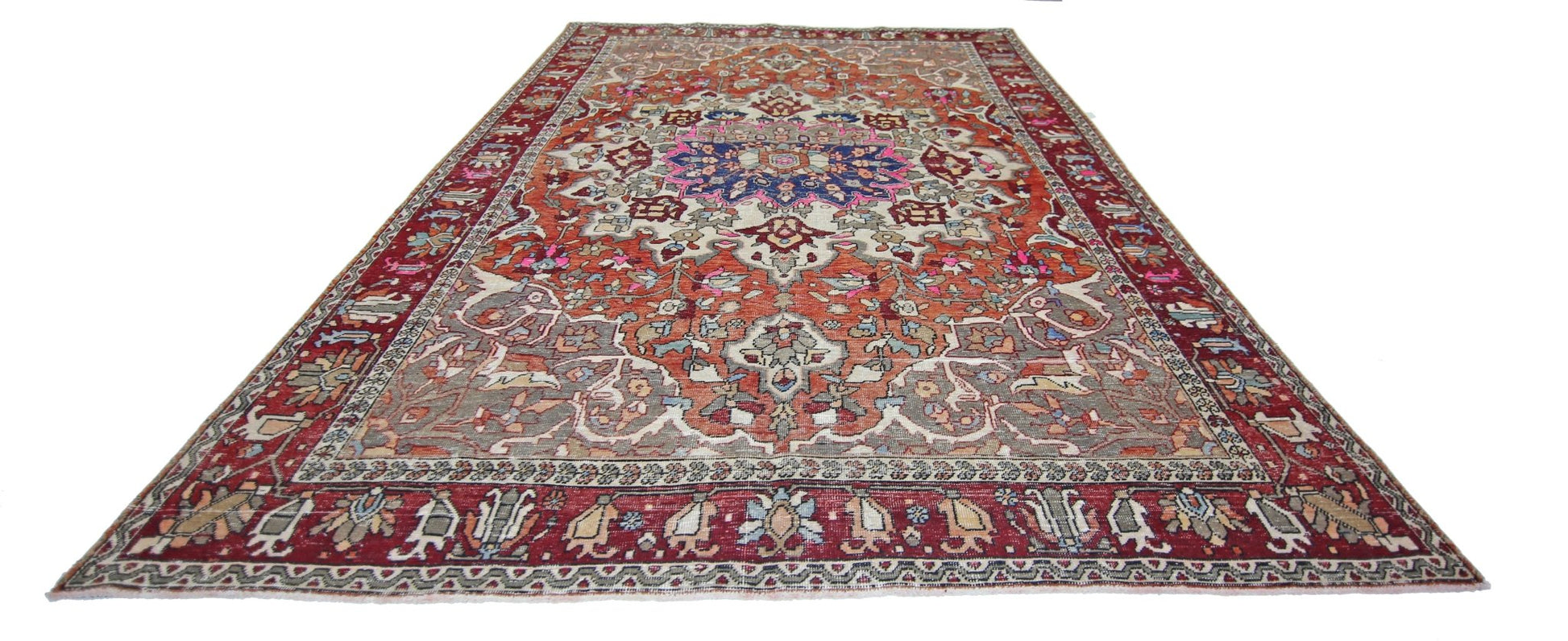 A vintage Persian Tabriz rug featuring a central floral medallion on a rust and cream background.
