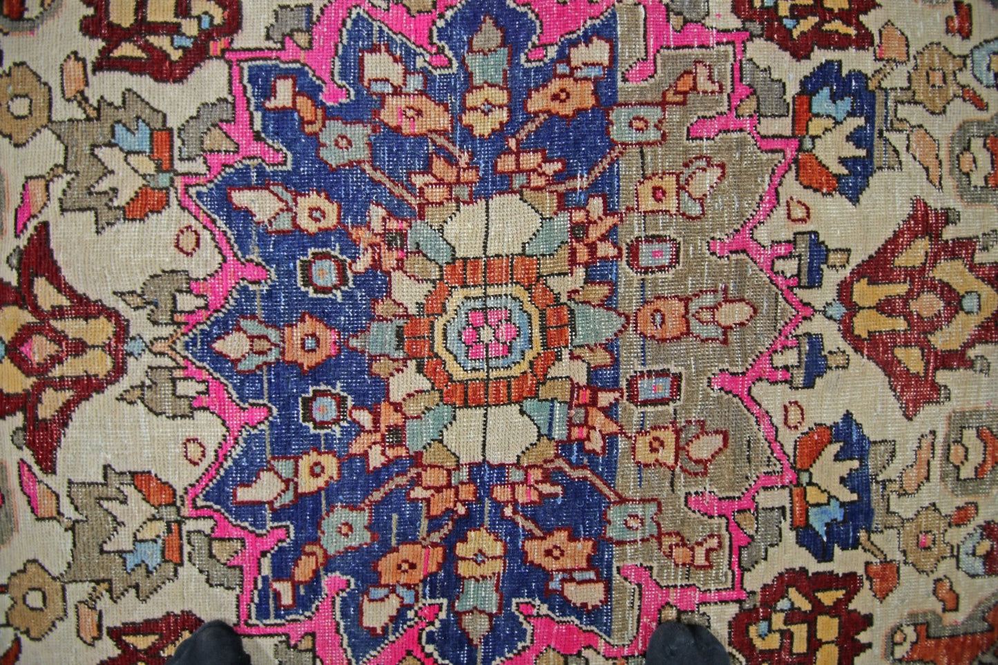 A vintage Persian Tabriz rug featuring a central floral medallion in blue, pink, and beige tones.