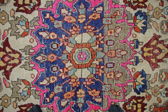 A vintage Persian Tabriz rug featuring a central floral medallion in blue, pink, and beige tones.