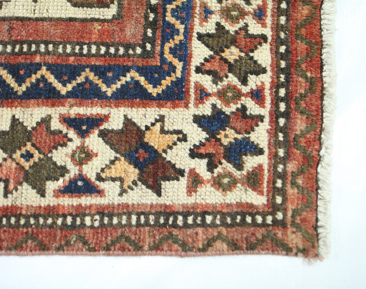 A corner view of a vintage Persian Bakhtiari rug featuring intricate geometric floral patterns.