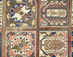A vintage Persian Bakhtiari rug featuring a geometric grid pattern with intricate floral motifs.