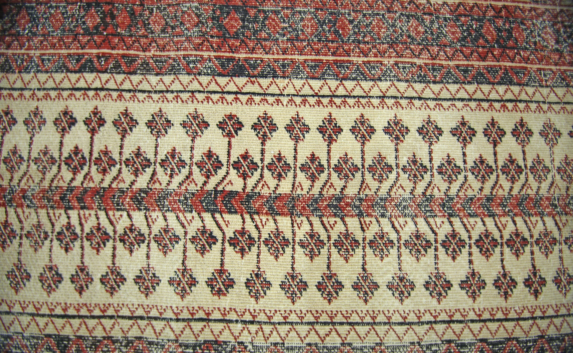 A vintage Persian Bakhtiari runner featuring geometric floral motifs in red and black on cream wool.