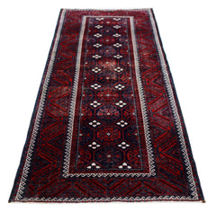 A handmade vintage Afghan Baluch runner rug featuring geometric patterns in deep red and navy blue.