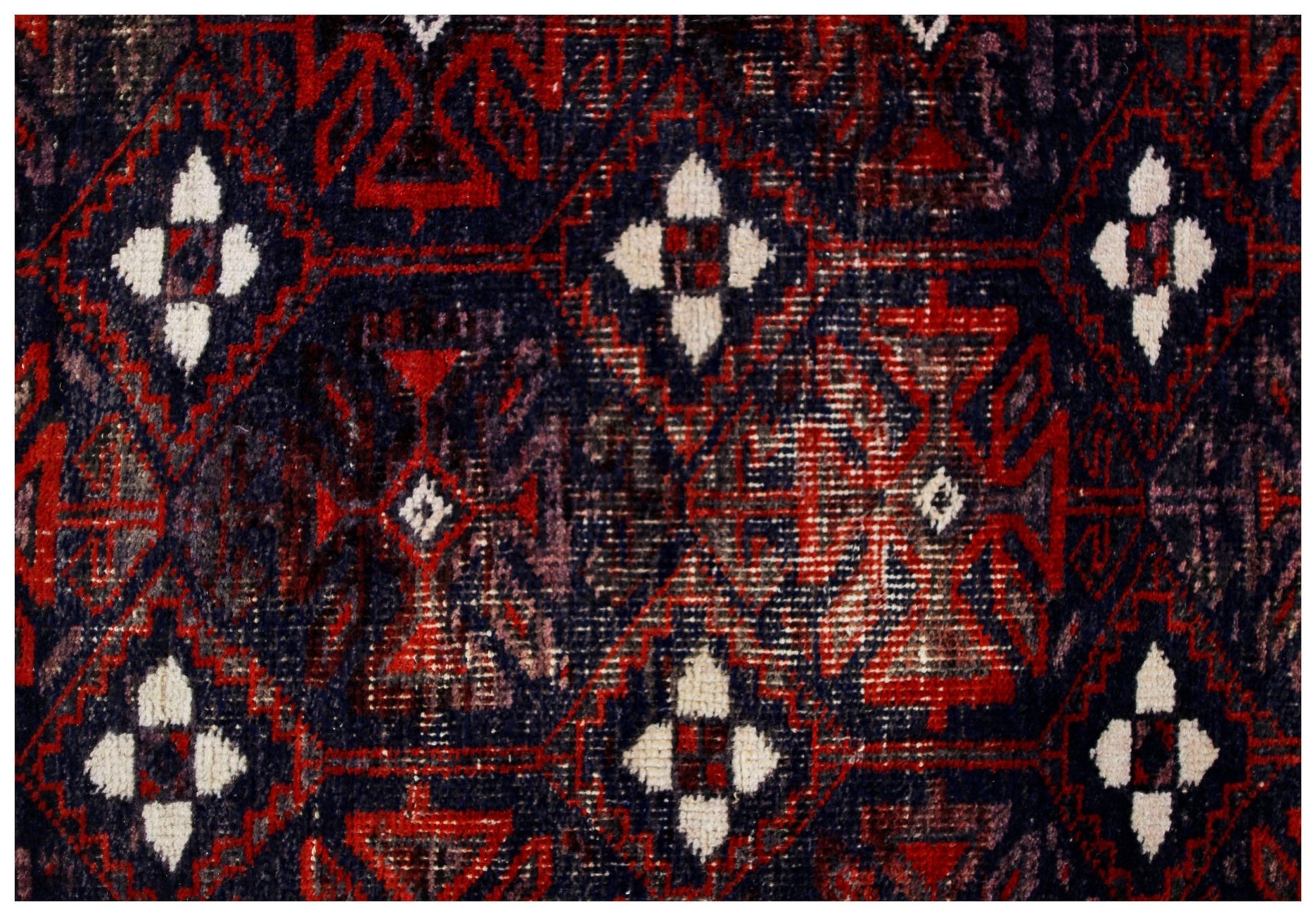 A vintage Afghan Baluch rug featuring a repeating geometric pattern in deep red and dark blue.