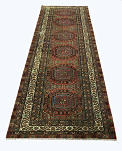 A vintage Persian Baluch runner featuring a geometric pattern in red, blue, and cream tones.