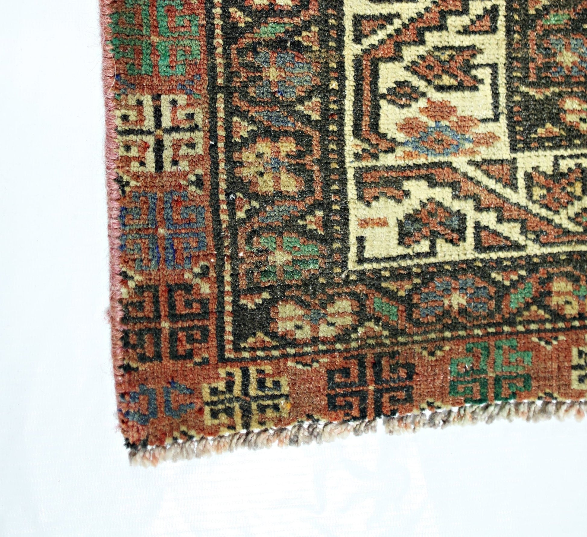 A corner view of a vintage Persian Baluch runner featuring geometric patterns in wool.