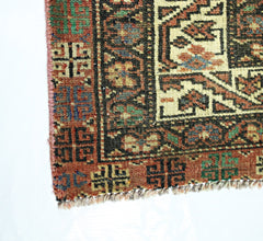 A corner view of a vintage Persian Baluch runner featuring geometric patterns in wool.
