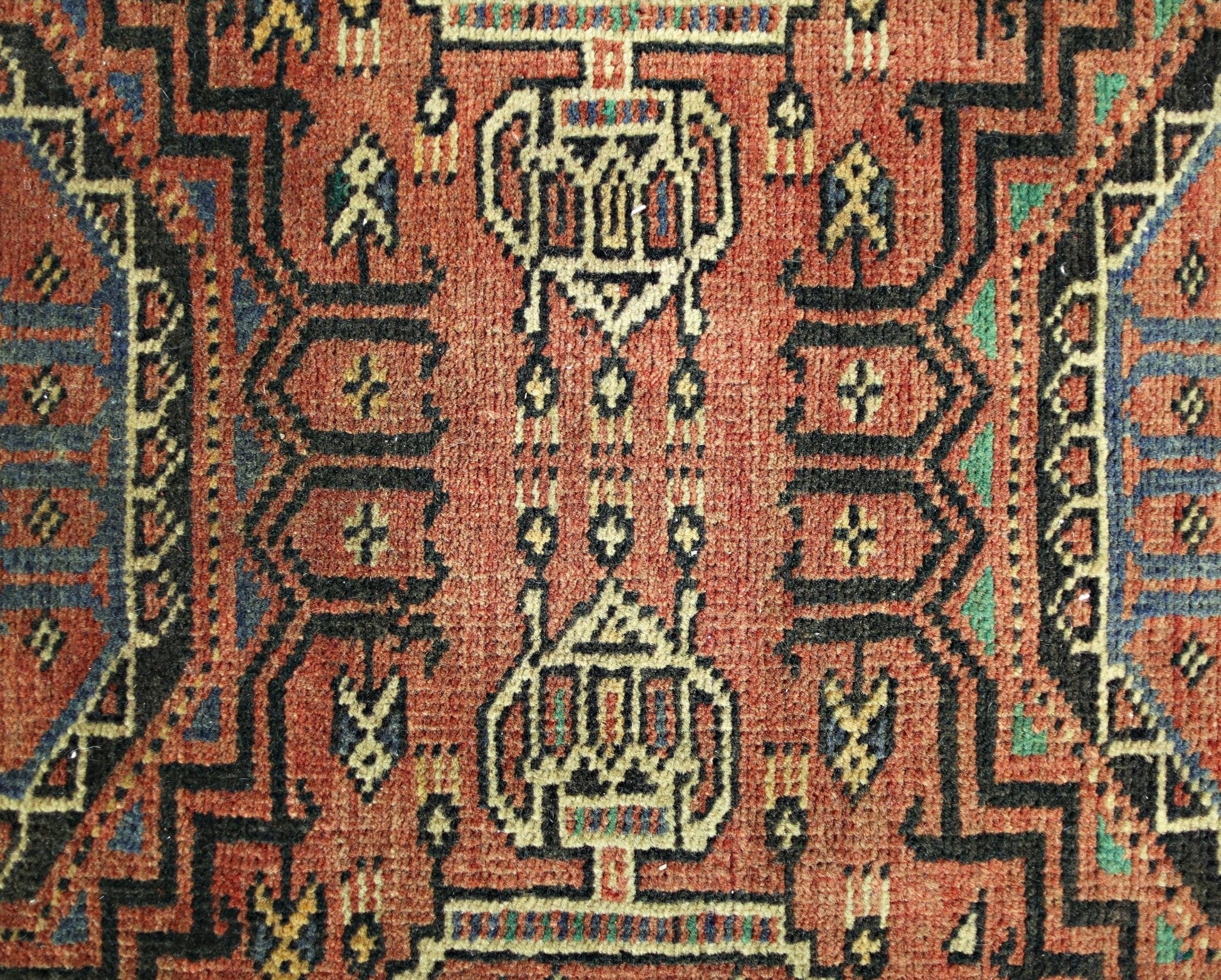 A vintage Persian Baluch runner featuring intricate geometric patterns in red, black, and blue.
