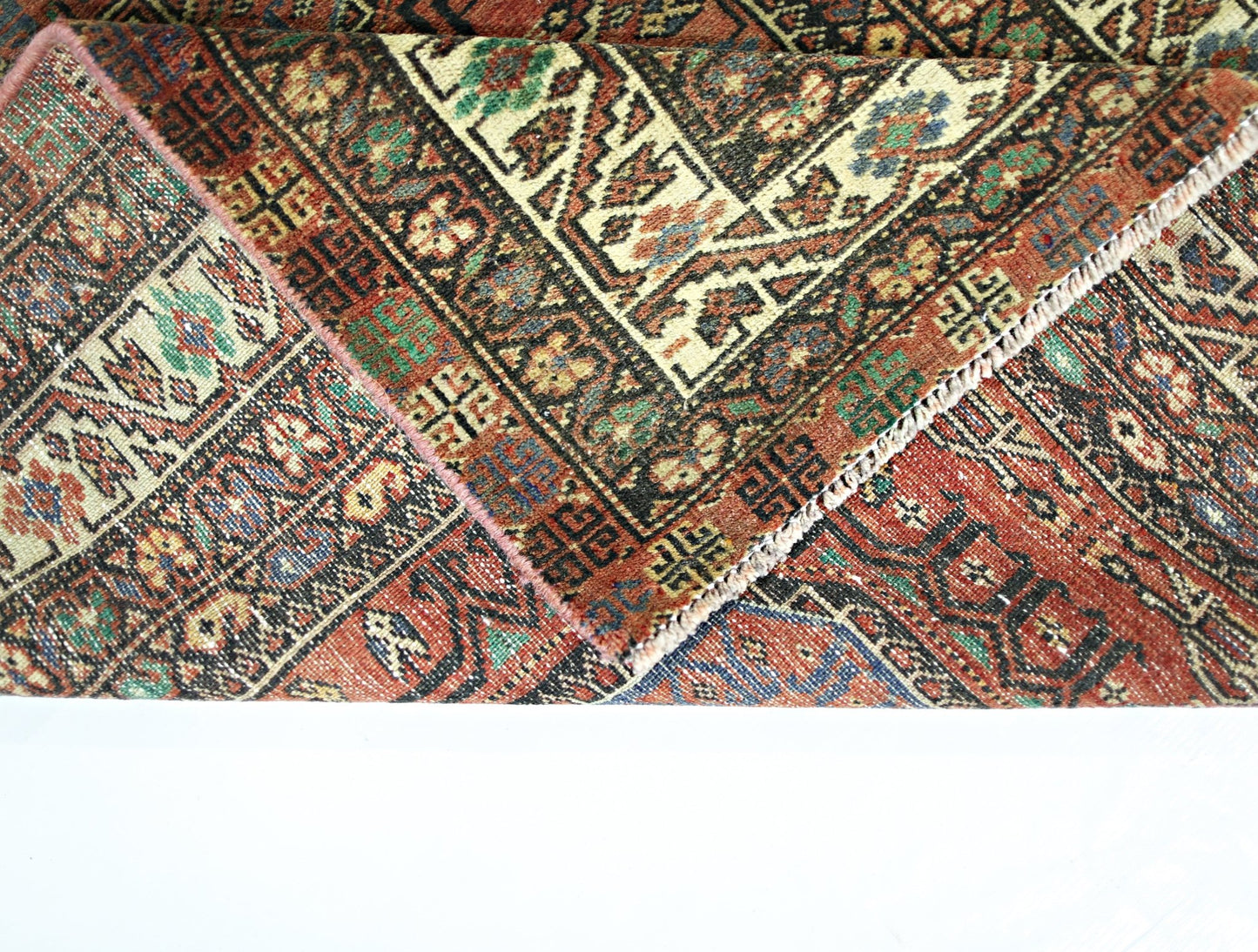 A vintage Persian Baluch runner featuring intricate geometric patterns in a rich, colorful palette.