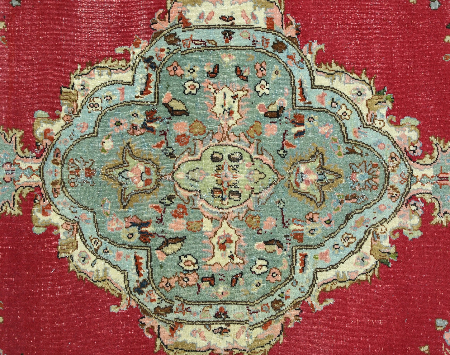 A vintage Persian Bidjar rug featuring a central floral medallion in teal on a red background.