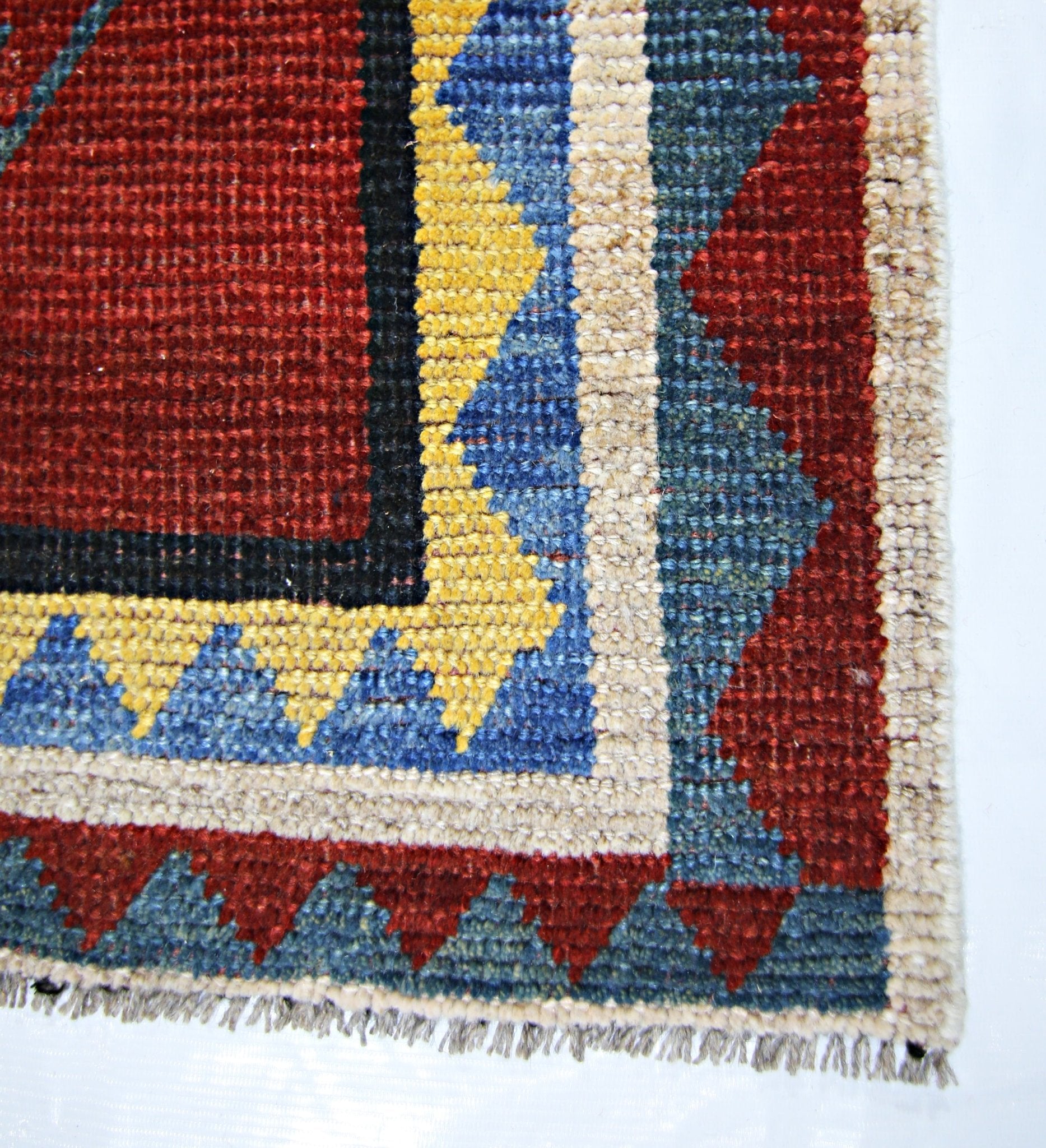 A corner view of a vintage Persian Shiraz rug featuring geometric patterns in red, blue, and yellow.