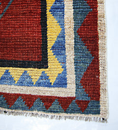 A corner view of a vintage Persian Shiraz rug featuring geometric patterns in red, blue, and yellow.