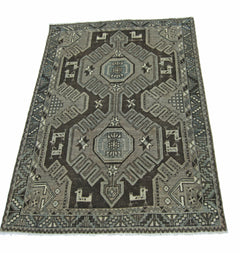 A vintage handmade Persian rug featuring a geometric pattern in shades of grey and brown.