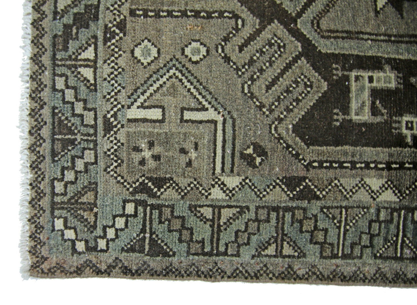 A vintage Persian rug featuring geometric patterns in shades of grey and brown.