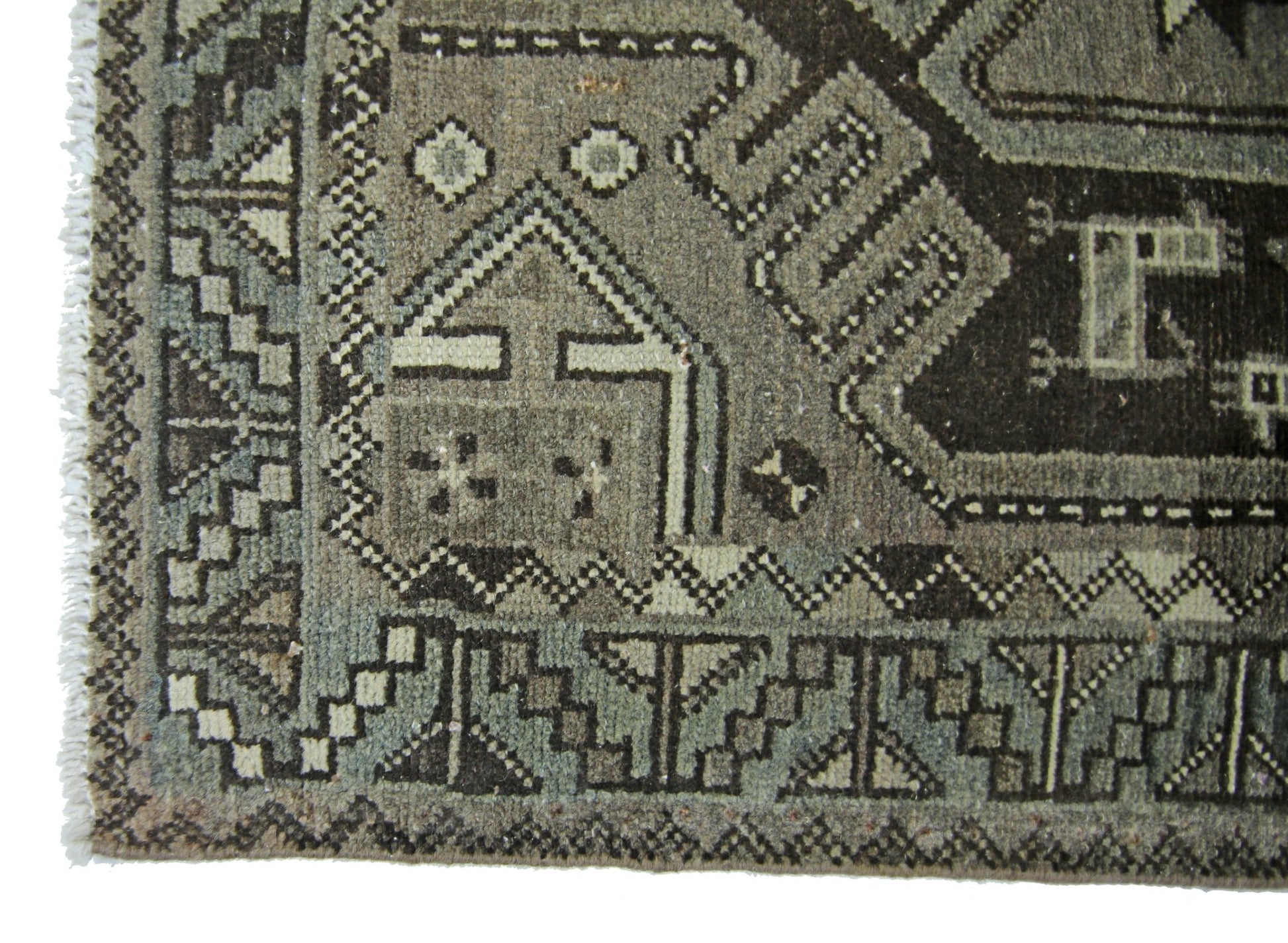A vintage Persian rug featuring geometric patterns in shades of grey and brown.