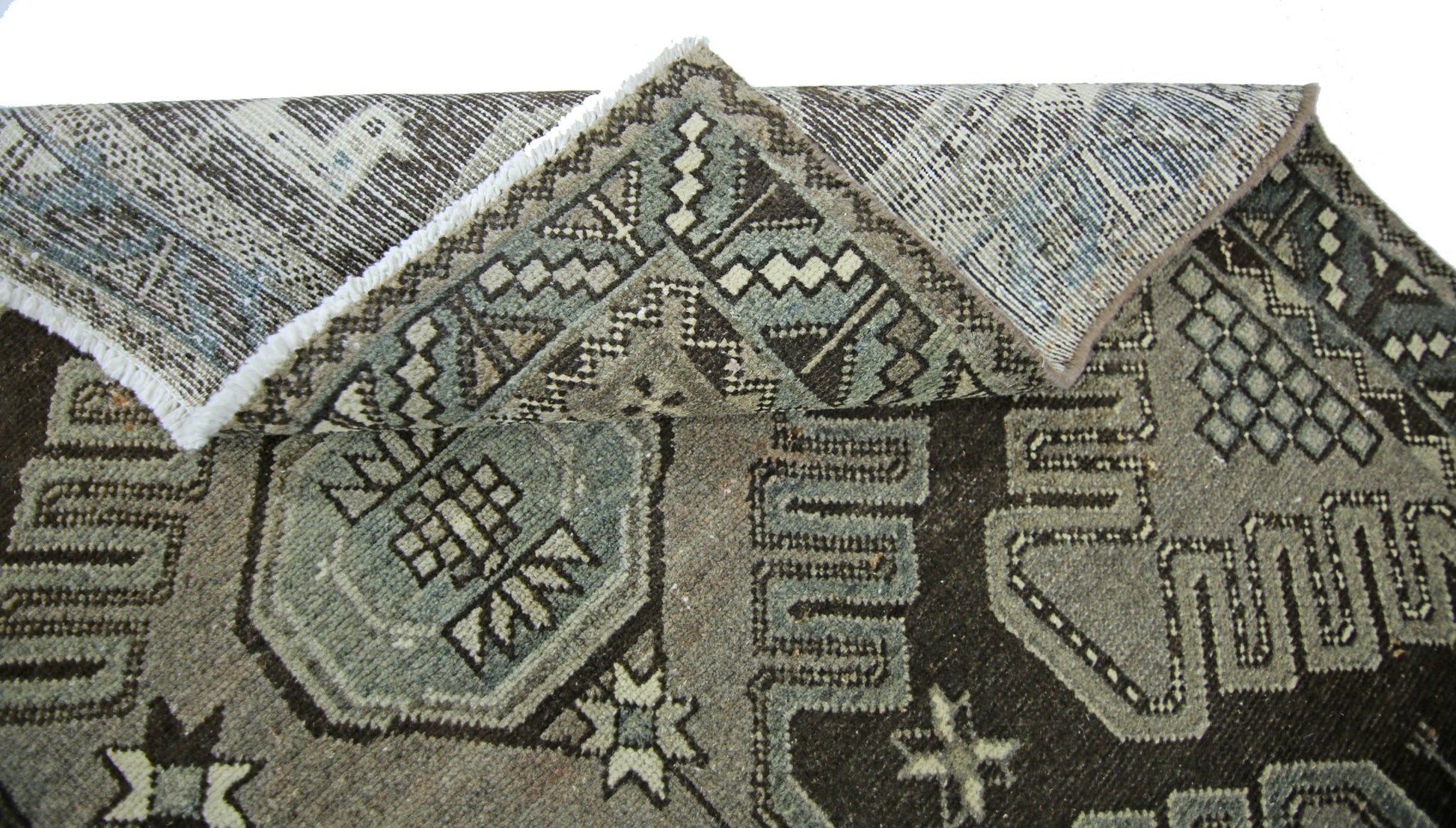 A vintage handmade Persian rug featuring geometric patterns in shades of brown and blue.
