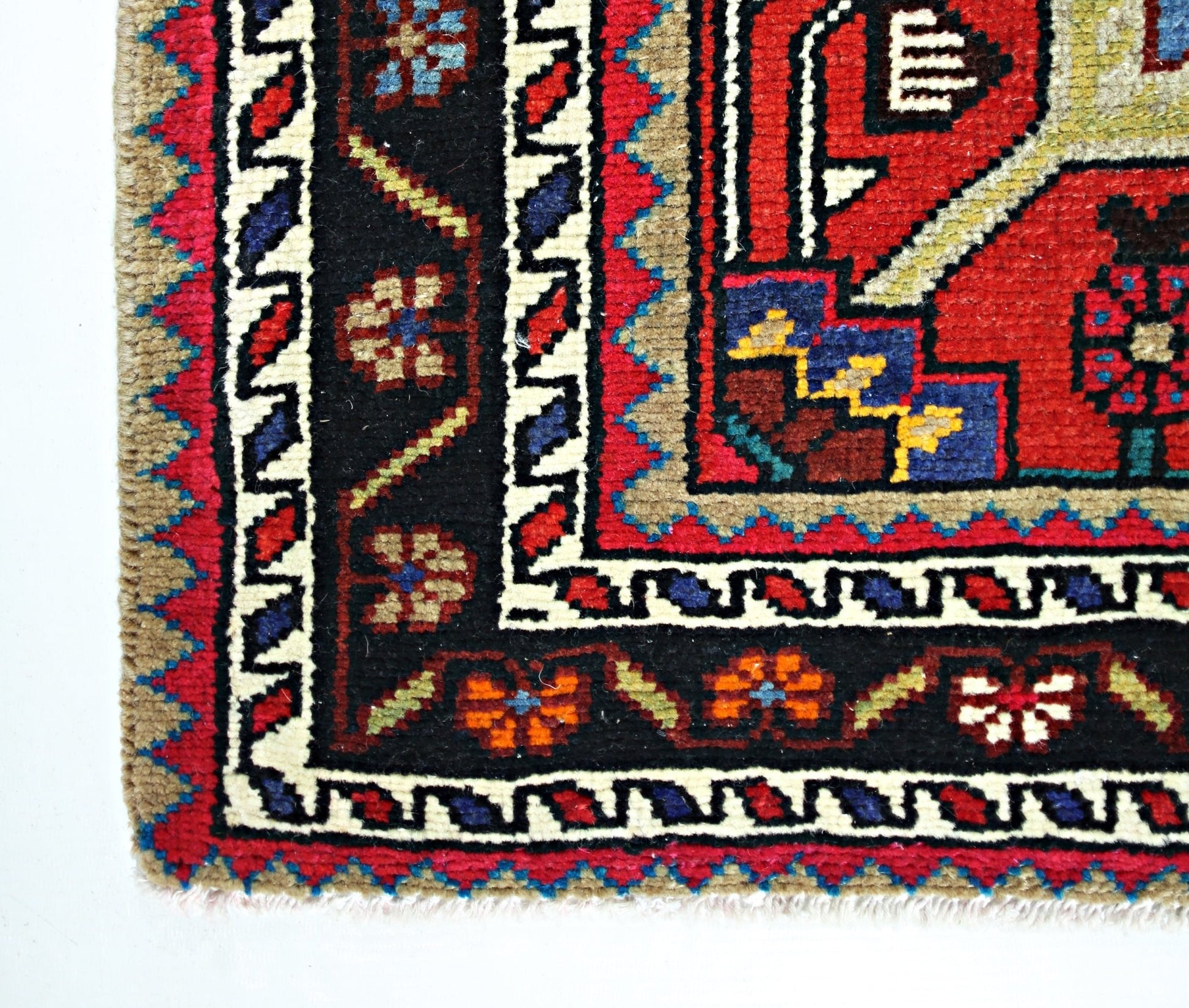 A corner view of a vintage Persian Hamadan rug featuring geometric floral patterns in wool.