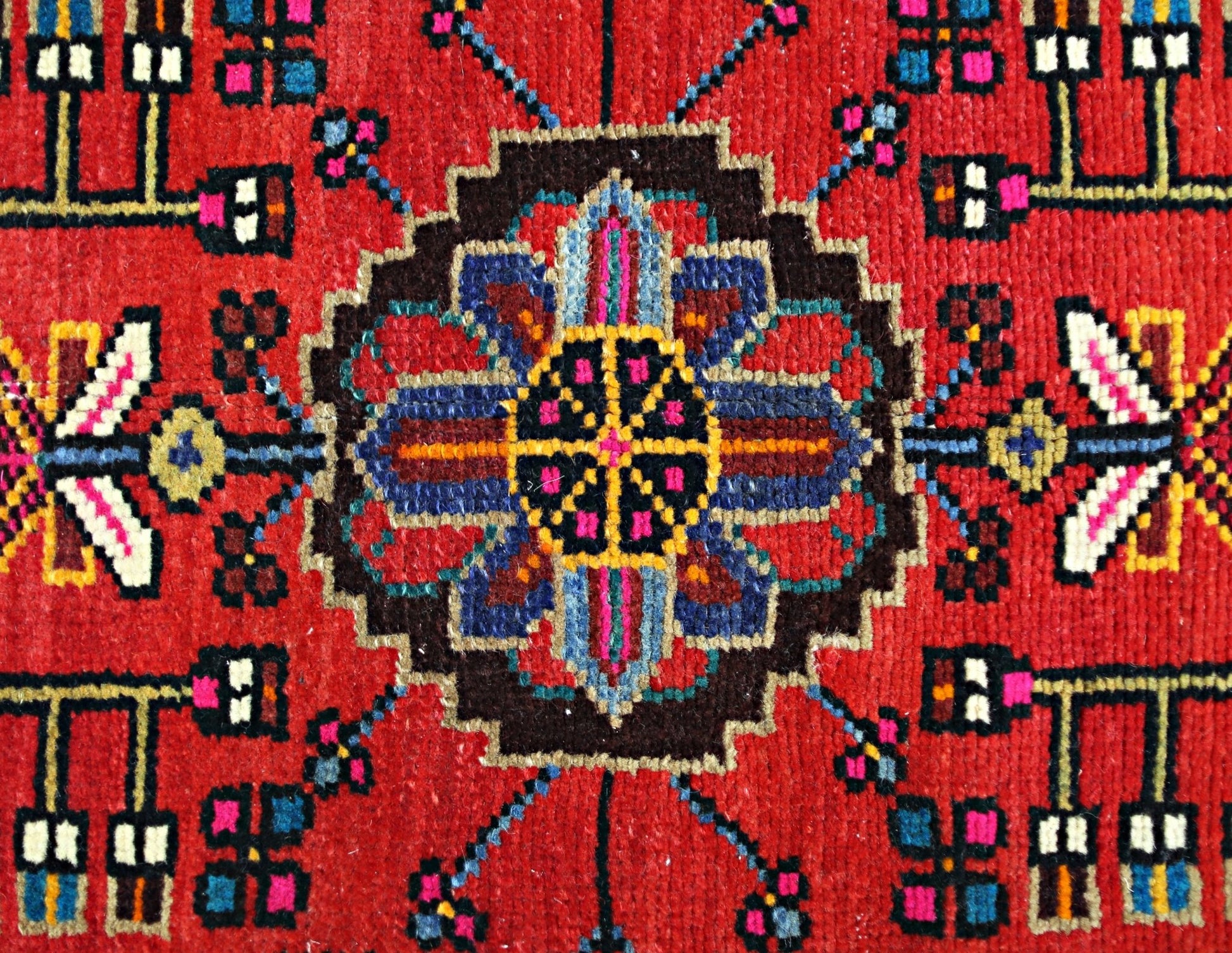 A vintage Persian Hamadan rug featuring a central geometric floral medallion on a red field.