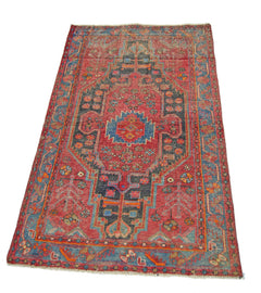 A vintage handmade Persian Hamadan rug featuring a geometric medallion on a red field.