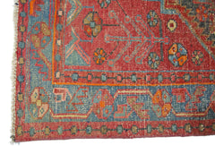 A vintage Persian Hamadan rug featuring a red field with blue geometric floral patterns and borders.