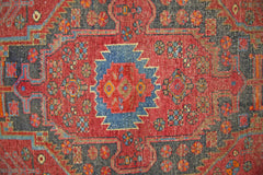A vintage Persian Hamadan rug featuring a geometric medallion pattern in red, blue, and tan wool.