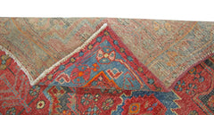 A corner of a vintage Persian Hamadan rug is folded back to reveal its wool pile and cotton base.