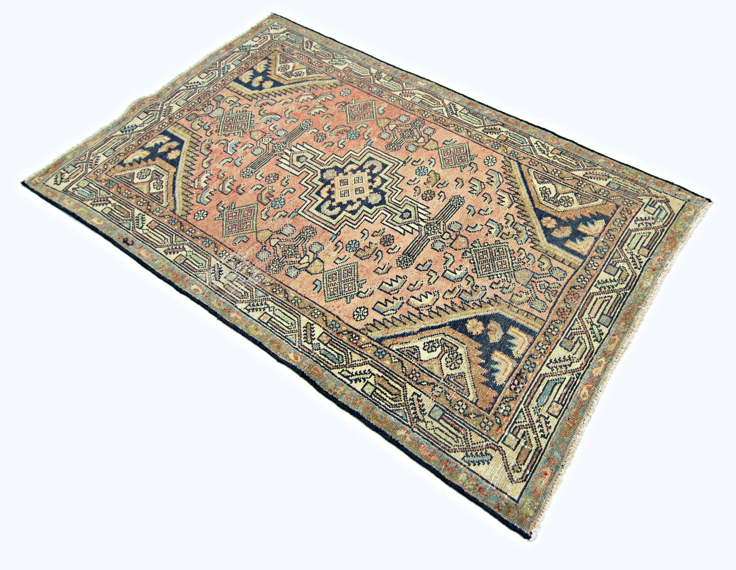 A rectangular vintage Persian rug featuring a central geometric medallion on a salmon field.