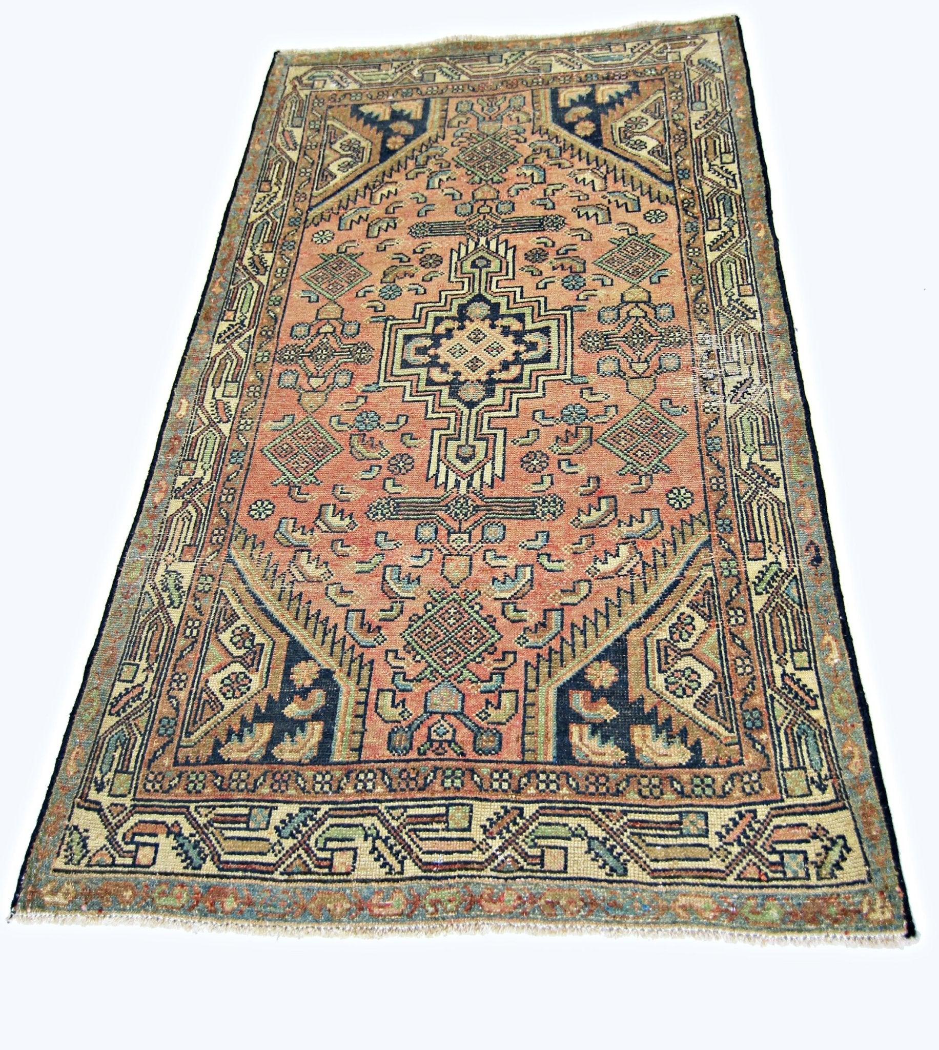 A vintage handmade Persian rug featuring a geometric medallion pattern in muted red and blue tones.