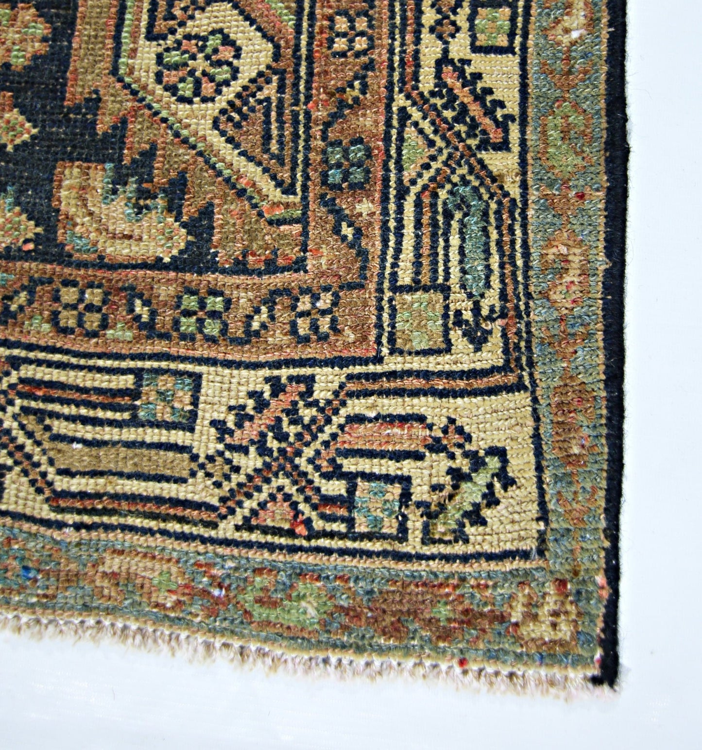 A close-up of a vintage handmade Persian rug featuring intricate geometric patterns in wool.