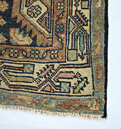 A close-up of a vintage handmade Persian rug featuring intricate geometric patterns in wool.