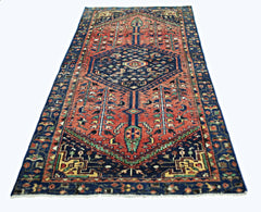 A vintage handmade Persian Hamadan rug featuring a geometric medallion on a red field.