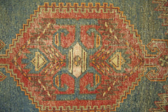 A vintage Persian Hamadan rug featuring a central geometric medallion in red, blue, and cream.