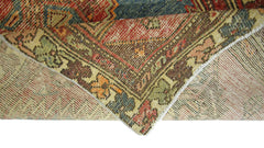 A corner of a vintage Persian Hamadan rug is folded back to reveal its wool pile and cotton base.