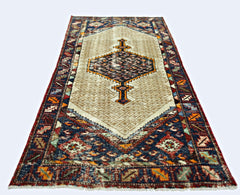 A vintage Persian Hamadan runner rug featuring a central geometric medallion on a beige field.