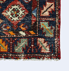 A vintage Persian Hamadan rug featuring a geometric pattern in red, blue, and green wool.
