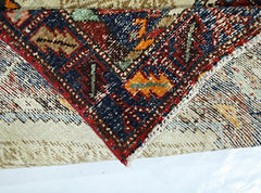 A corner of a vintage Persian Hamadan rug showing intricate geometric patterns in wool.
