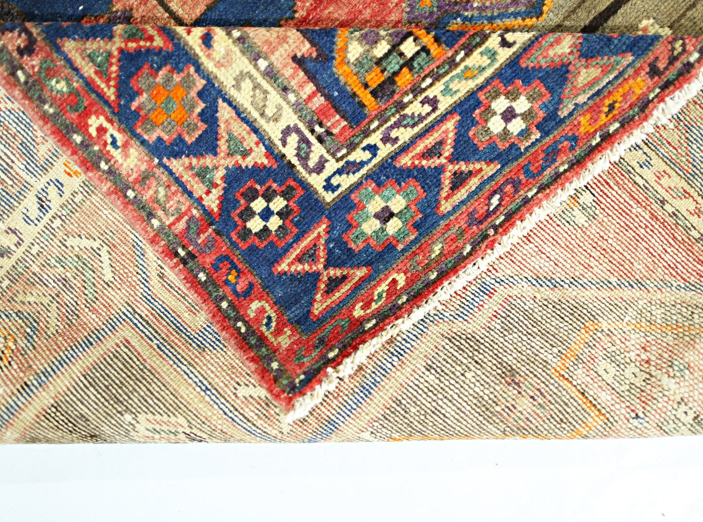 A corner of a vintage Persian Hamadan rug showing a blue border with geometric patterns.