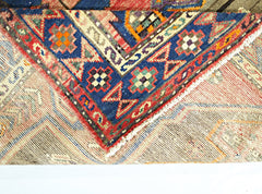 A corner of a vintage Persian Hamadan rug showing a blue border with geometric patterns.