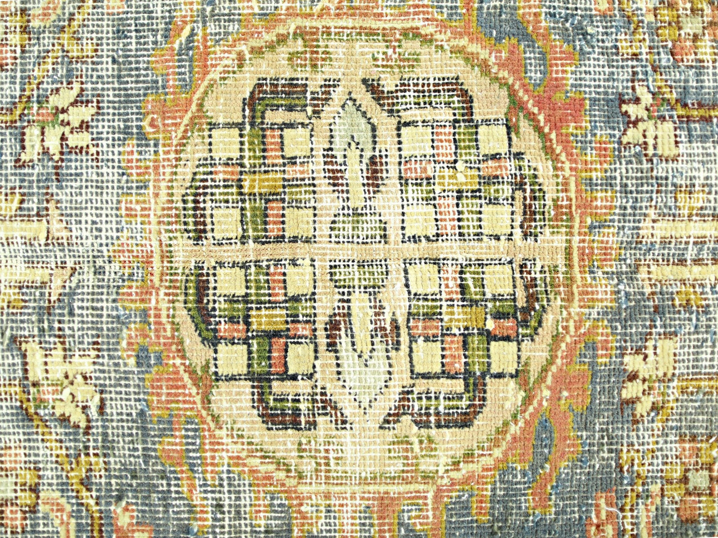 A close-up view of a vintage Persian rug featuring a geometric medallion in muted earth tones.