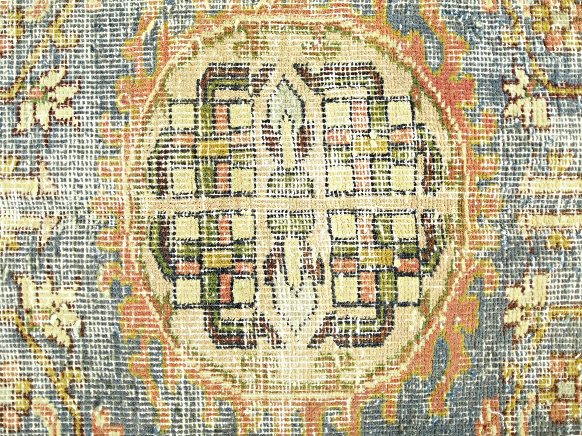 A close-up view of a vintage Persian rug featuring a geometric medallion in muted earth tones.